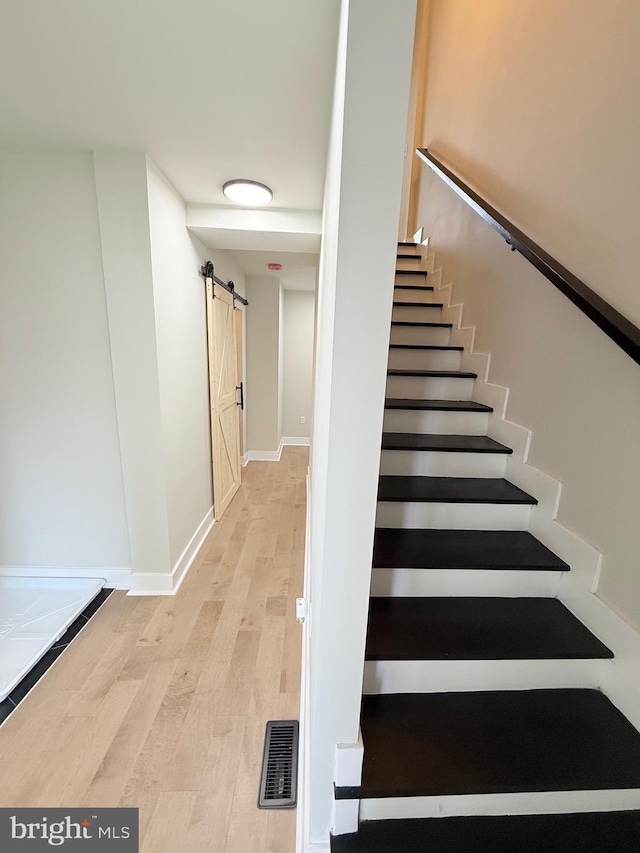 2112 Llewelyn Ave, Baltimore, MD 21213 - staircase featuring a barn door, wood finished floors, and baseboards