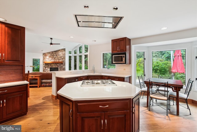6662 Van Winkle Dr, Falls Church, VA 22044 - kitchen with gas cooktop, ceiling fan, a stone fireplace, stainless steel microwave, and light wood-style flooring