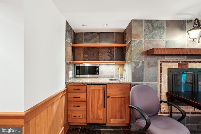 6662 Van Winkle Dr, Falls Church, VA 22044 - kitchen with stainless steel microwave, open shelves, light stone countertops, wainscoting, and brown cabinetry