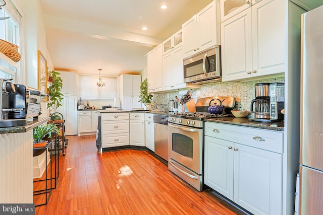 922 8th Ave, Prospect Park, PA 19076 - kitchen with stainless steel appliances, dark countertops, backsplash, white cabinets, and glass insert cabinets