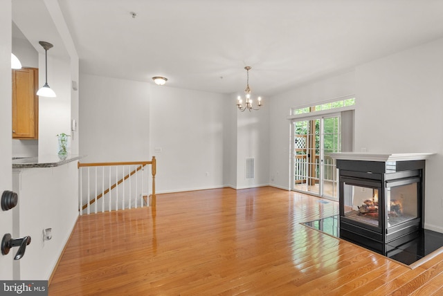 13800 Breezy Ridge Way Unit 101, Woodbridge, VA 22191 - unfurnished living room with light wood-style flooring, a chandelier, baseboards, and a multi sided fireplace