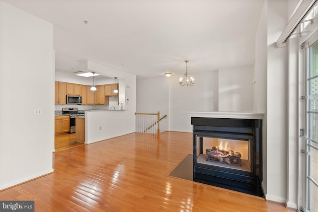 13800 Breezy Ridge Way Unit 101, Woodbridge, VA 22191 - unfurnished living room with light wood finished floors, a chandelier, a multi sided fireplace, a sink, and baseboards