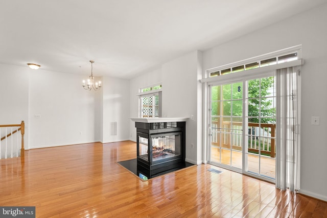 13800 Breezy Ridge Way Unit 101, Woodbridge, VA 22191 - unfurnished living room featuring wood finished floors, a chandelier, a multi sided fireplace, and baseboards