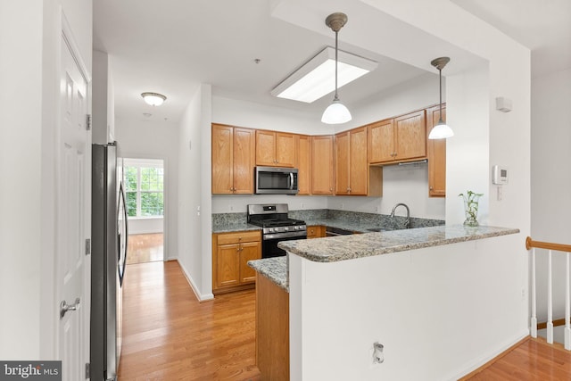 13800 Breezy Ridge Way Unit 101, Woodbridge, VA 22191 - kitchen with stainless steel appliances, a peninsula, light wood-style floors, hanging light fixtures, and a sink