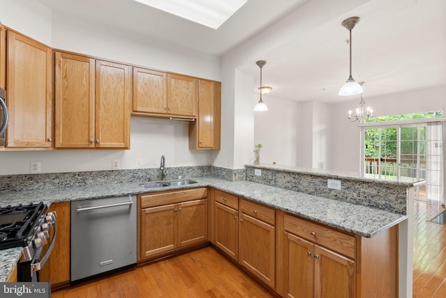 13800 Breezy Ridge Way Unit 101, Woodbridge, VA 22191 - kitchen featuring appliances with stainless steel finishes, a sink, a peninsula, light wood-style floors, and light stone counters