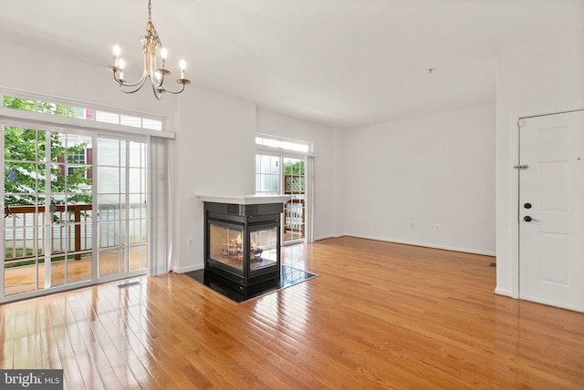 13800 Breezy Ridge Way Unit 101, Woodbridge, VA 22191 - unfurnished living room with light wood-type flooring, a chandelier, a multi sided fireplace, and baseboards