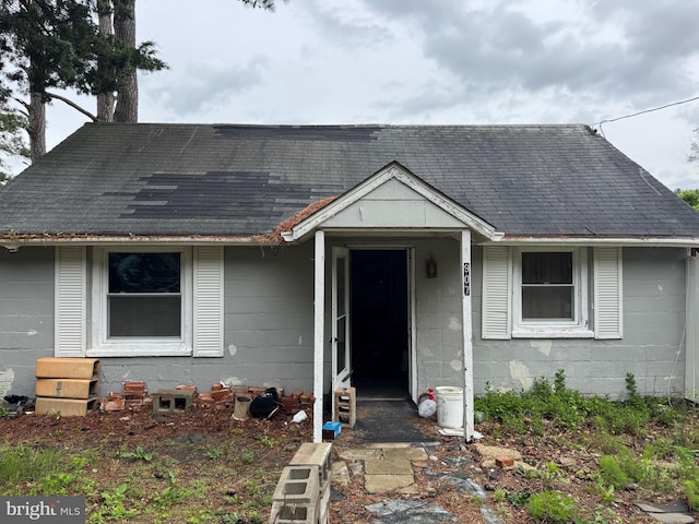 view of front of house with concrete block siding and a shingled roof