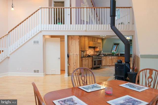 4027 Trego Mountain Rd, Keedysville, MD 21756 - dining space featuring a wood stove, a high ceiling, light wood finished floors, stairs, and baseboards