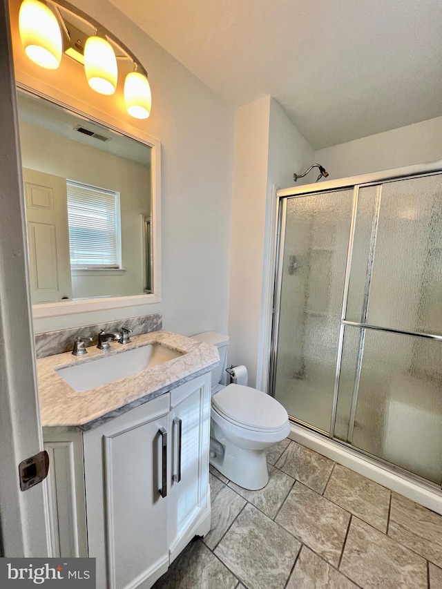bathroom featuring a stall shower, vanity, and toilet