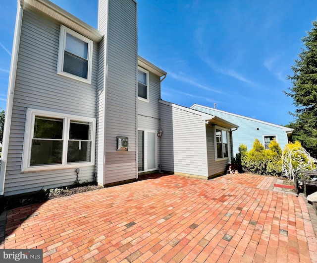 back of house with a patio and a chimney
