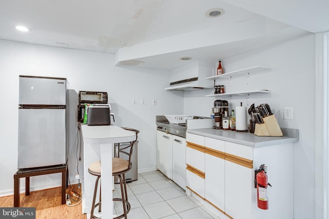 5518 Kempton Dr, Springfield, VA 22151 - kitchen with freestanding refrigerator, under cabinet range hood, light countertops, white cabinets, and recessed lighting