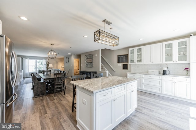 515 Williamsburg Way, King Of Prussia, PA 19406 - kitchen with freestanding refrigerator, a chandelier, glass insert cabinets, a kitchen island, and wood finished floors
