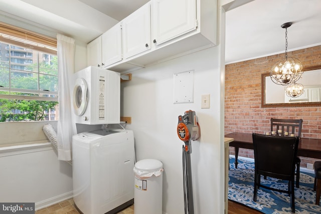 6034 Westchester Park Dr Unit 202, College Park, MD 20740 - laundry room with stacked washer / dryer, cabinet space, baseboards, a chandelier, and brick wall