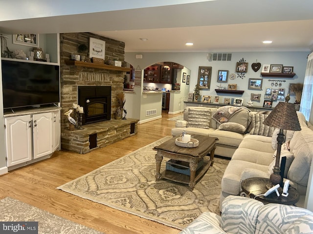569 Highbank Rd, Severna Park, MD 21146 - living room featuring arched walkways, crown molding, a fireplace, light wood-style flooring, and recessed lighting