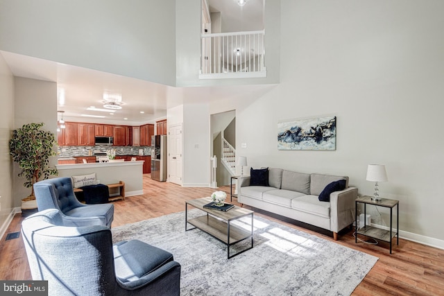 857 Barcelona St, Townsend, DE 19734 - living area featuring light wood-style flooring, stairway, baseboards, and a high ceiling
