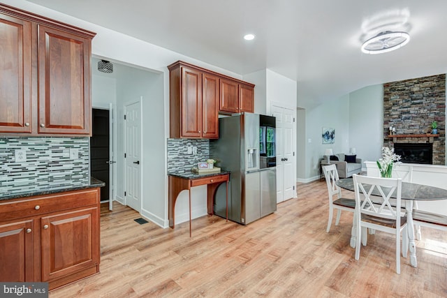 857 Barcelona St, Townsend, DE 19734 - kitchen featuring stainless steel fridge with ice dispenser, light wood-style floors, decorative backsplash, open floor plan, and a stone fireplace