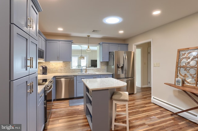 1138 S Green St, Palmyra, PA 17078 - kitchen featuring stainless steel appliances, baseboard heating, a sink, tasteful backsplash, and a kitchen bar
