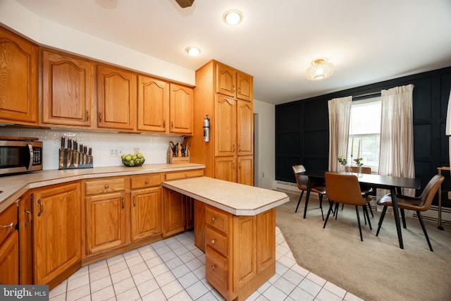 200 Maplewood Dr Unit 20, Pottstown, PA 19464 - kitchen featuring light countertops, stainless steel microwave, decorative backsplash, and brown cabinets