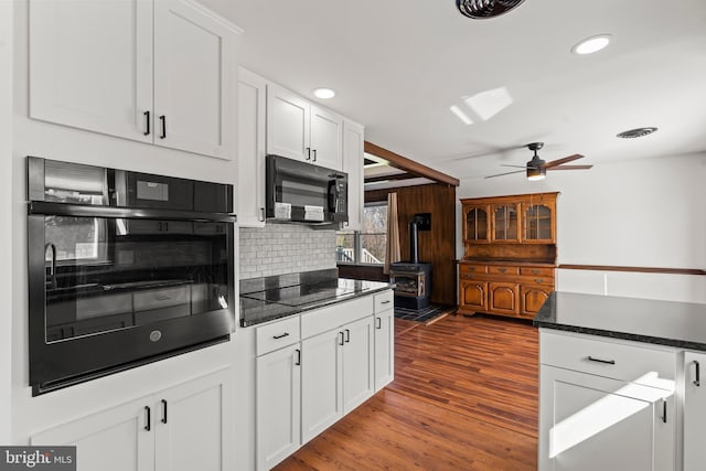 18000 Davis Ln, Boonsboro, MD 21713 - kitchen with black appliances, a wood stove, tasteful backsplash, white cabinetry, and dark wood finished floors
