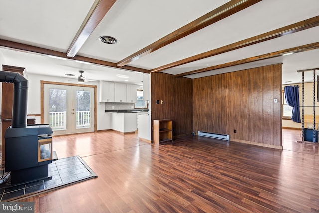 18000 Davis Ln, Boonsboro, MD 21713 - unfurnished living room featuring a baseboard radiator, a ceiling fan, a wood stove, beam ceiling, and wood finished floors