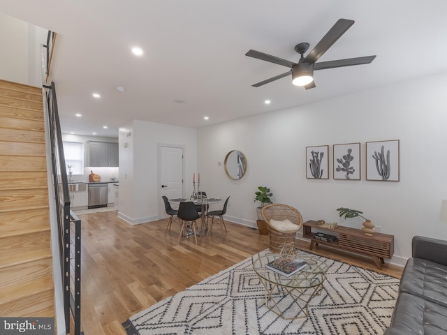 living room with a ceiling fan, light wood-style flooring, recessed lighting, baseboards, and stairway