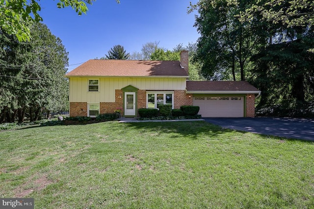 5330 Birney Hwy, Aston, PA 19014 - view of front of home with a chimney, an attached garage, a front yard, brick siding, and asphalt driveway