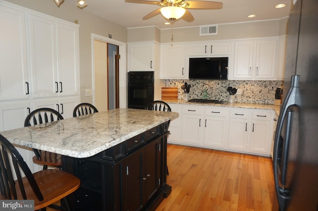 1331 Bradley Ave, Hummelstown, PA 17036 - kitchen with black appliances, a kitchen bar, a ceiling fan, white cabinetry, and tasteful backsplash