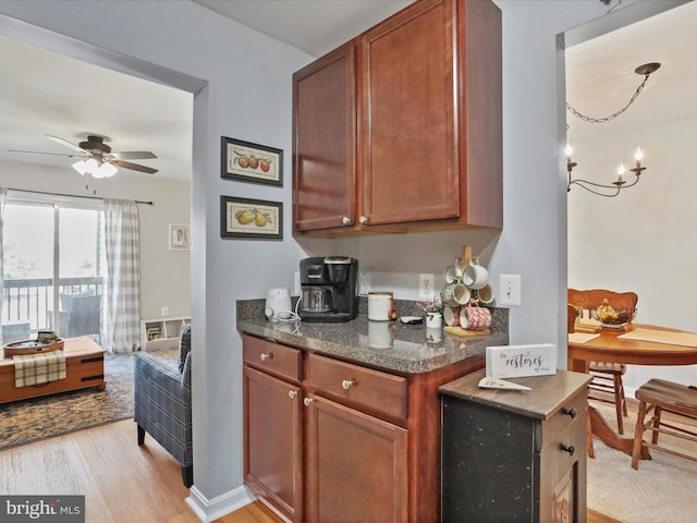 108 Timberlake Ter Unit 7, Stephens City, VA 22655 - kitchen with light wood-type flooring, ceiling fan, dark stone counters, a chandelier, and brown cabinets