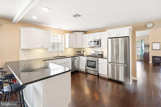 53 Stockport Dr, Toms River, NJ 08757 - kitchen featuring appliances with stainless steel finishes, a peninsula, white cabinets, a sink, and dark stone countertops