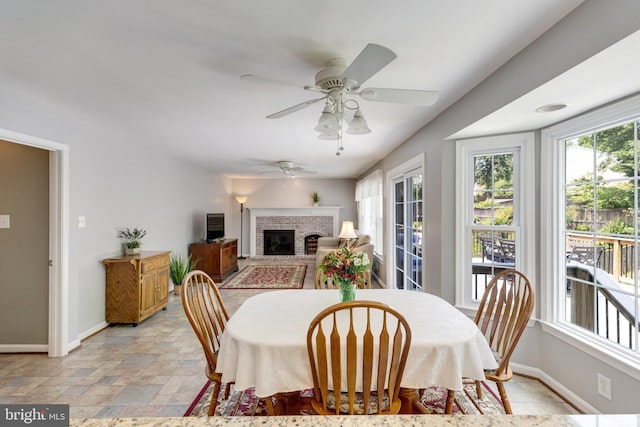 8314 Graceway Dr, Lorton, VA 22079 - dining room featuring baseboards, light stone finish floors, a brick fireplace, and a ceiling fan