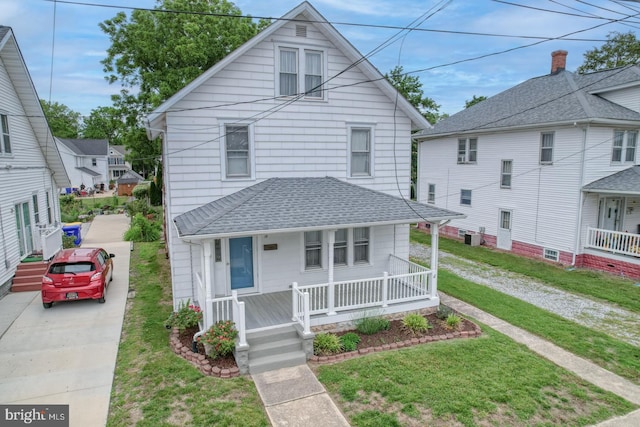 12 W Mispillion St, Harrington, DE 19952 - traditional style home featuring covered porch, a shingled roof, a front lawn, and central AC unit