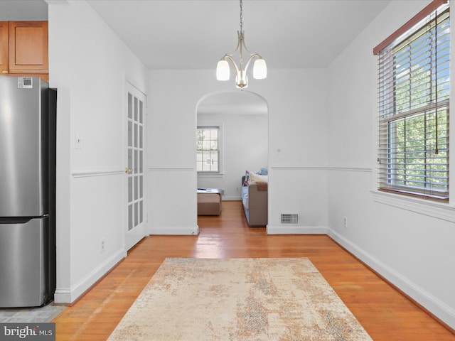 3912 13th St S, Arlington, VA 22204 - unfurnished dining area with arched walkways, light wood-type flooring, a chandelier, and baseboards