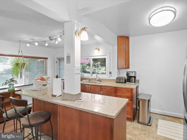 3912 13th St S, Arlington, VA 22204 - kitchen featuring a sink, brown cabinetry, a breakfast bar area, and light stone countertops