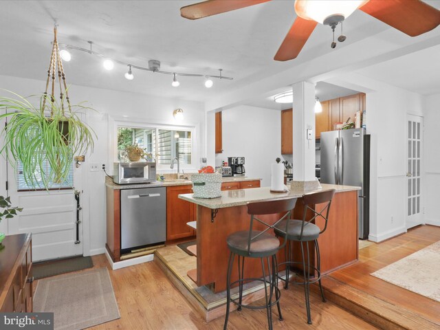 3912 13th St S, Arlington, VA 22204 - kitchen featuring stainless steel appliances, brown cabinets, light wood-style floors, a breakfast bar area, and a sink