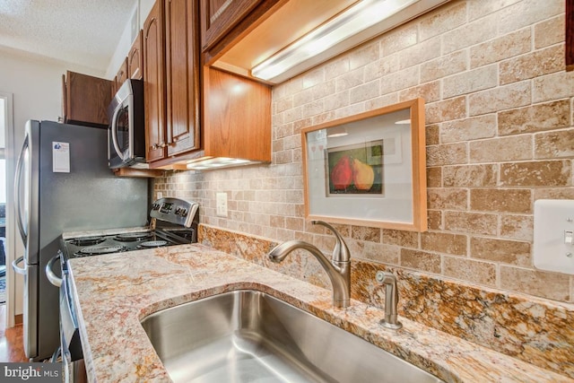 5904 Mount Eagle Dr Unit 1105, Alexandria, VA 22303 - kitchen with appliances with stainless steel finishes, brown cabinets, a sink, light stone countertops, and tasteful backsplash