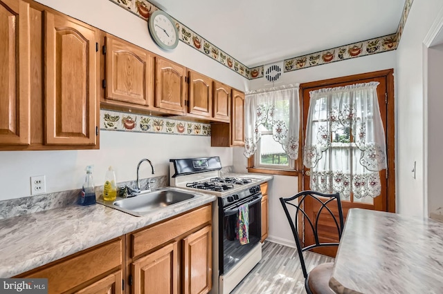 1210 Delbert Ave, Baltimore, MD 21222 - kitchen featuring range with gas cooktop, a sink, light countertops, light wood-type flooring, and brown cabinetry