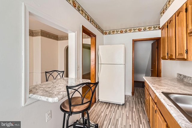 1210 Delbert Ave, Baltimore, MD 21222 - kitchen featuring freestanding refrigerator, light countertops, light wood-style flooring, a sink, and a kitchen bar