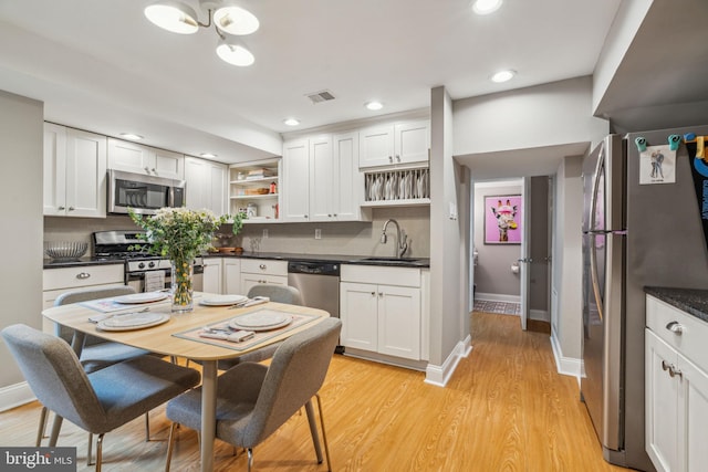 403 S Alder St, Philadelphia, PA 19147 - kitchen with open shelves, appliances with stainless steel finishes, a sink, dark countertops, and white cabinetry