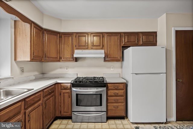 2428 Pliner Ct, Atco, NJ 08004 - kitchen with freestanding refrigerator, stainless steel gas range oven, under cabinet range hood, light countertops, and brown cabinetry