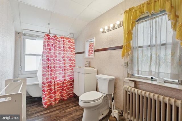 full bathroom featuring radiator heating unit, wood finished floors, toilet, a shower with curtain, and a bath