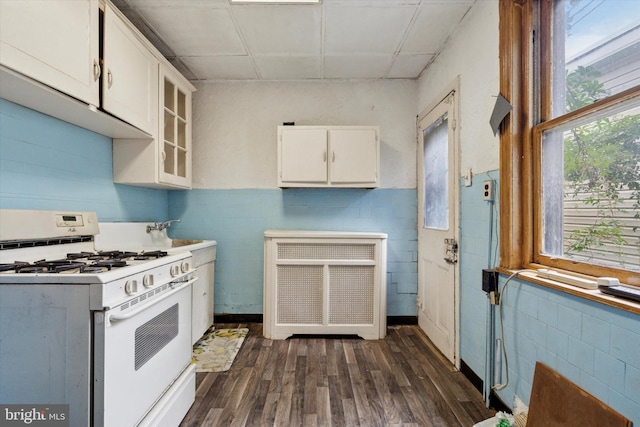 kitchen with white range with gas cooktop, dark wood-type flooring, white cabinets, glass insert cabinets, and light countertops