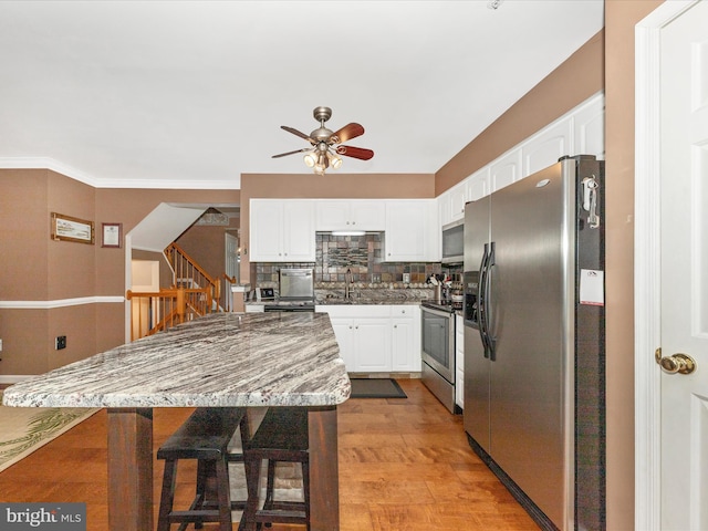 5500 Upshur Sq, Frederick, MD 21703 - kitchen with appliances with stainless steel finishes, ceiling fan, white cabinetry, a sink, and backsplash