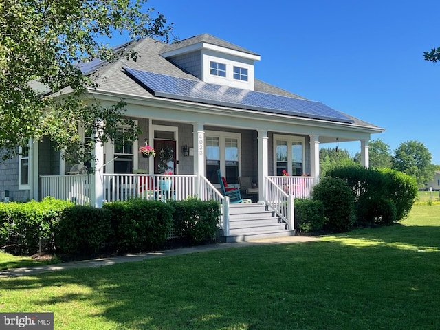 bungalow-style house with a porch, roof mounted solar panels, a front lawn, and a shingled roof