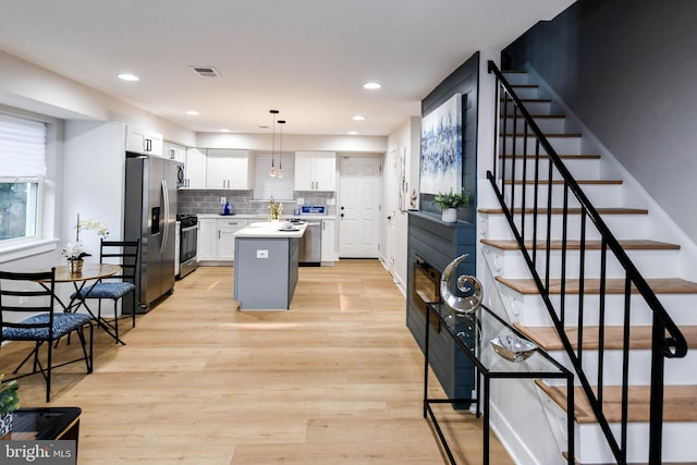 711 57th Pl NE, Washington, DC 20019 - kitchen featuring stainless steel fridge with ice dispenser, white cabinetry, gas range oven, a kitchen island, and light countertops