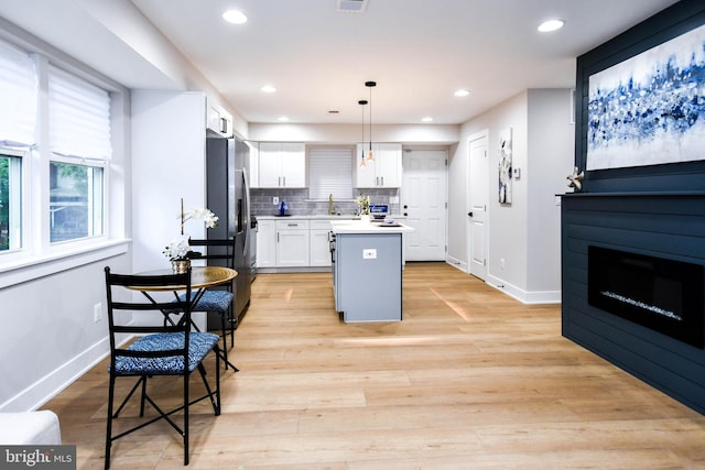 711 57th Pl NE, Washington, DC 20019 - kitchen with white cabinetry, a kitchen island, tasteful backsplash, stainless steel refrigerator with ice dispenser, and baseboards