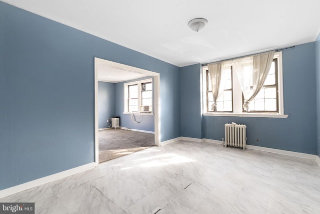 empty room featuring radiator and baseboards