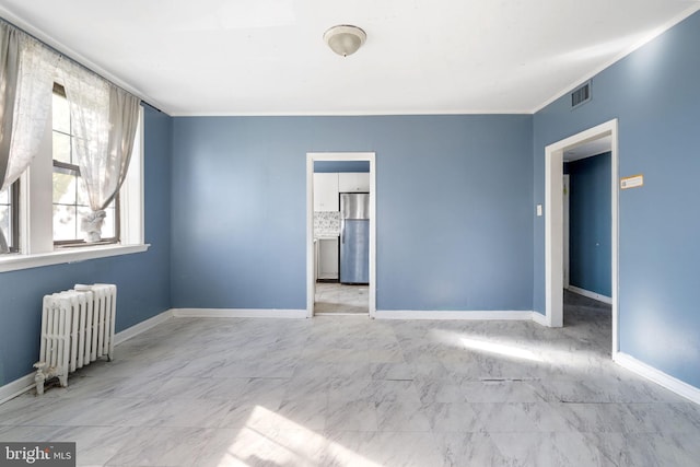 empty room featuring radiator, baseboards, and ornamental molding