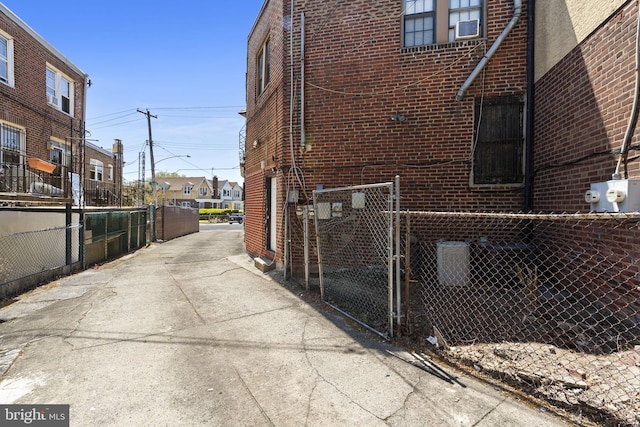 view of side of property featuring brick siding, a gate, and cooling unit