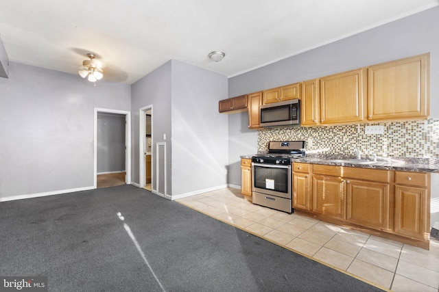 kitchen with stainless steel appliances, dark countertops, a sink, and tasteful backsplash