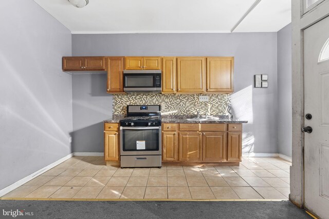 kitchen with stainless steel appliances, backsplash, light tile patterned floors, and baseboards